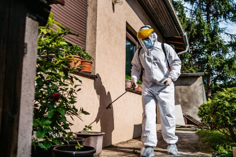 Person in protective gear fumigating a backyard to get rid of pests